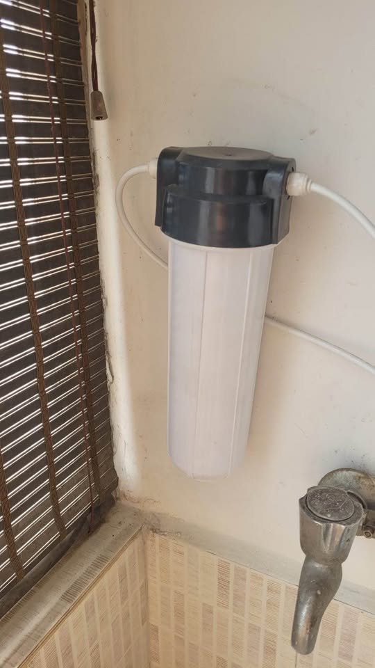 External pre filter for Aquaguard Enrich Aura 2X RO showing wall mounted sediment filter housing with inlet and outlet water tubes