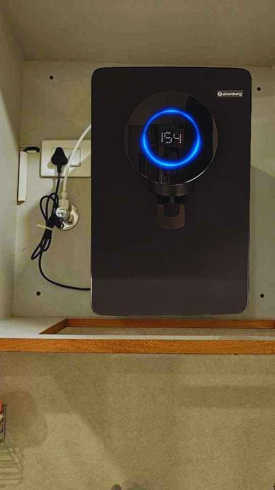 Atomberg Intellon RO water purifier with realtime TDS display showing a reading of 154 on the front panel